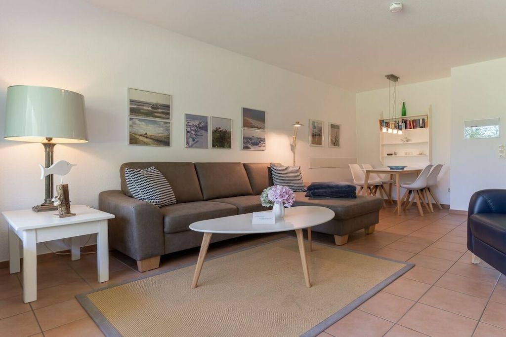 A modern living room with a sofa, coffee table, and a dining area with chairs and a table.