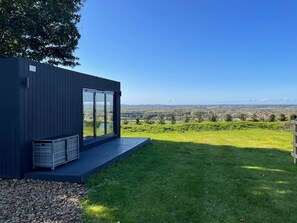 A modern building with large windows, a grassy lawn, and a view of distant hills. - Animal Crossing (Southam)
