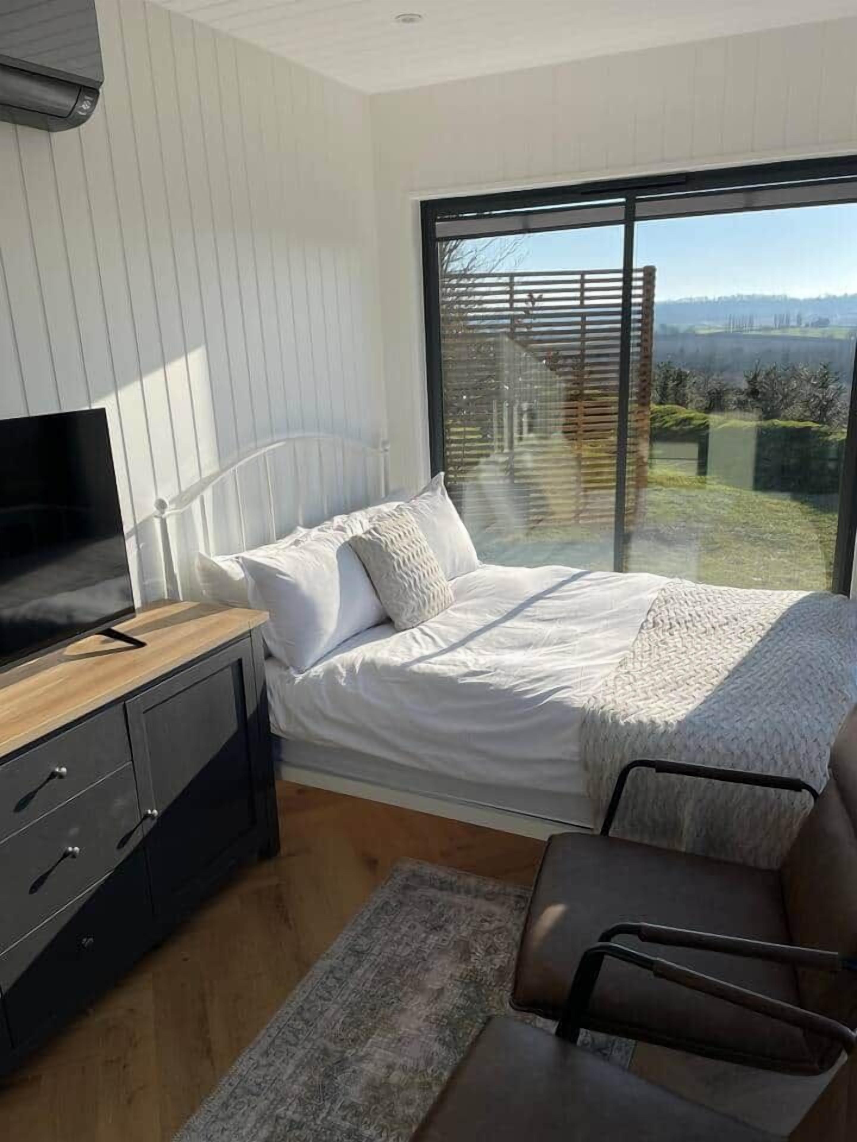 A bedroom with a bed, a TV, a desk, and a chair.
