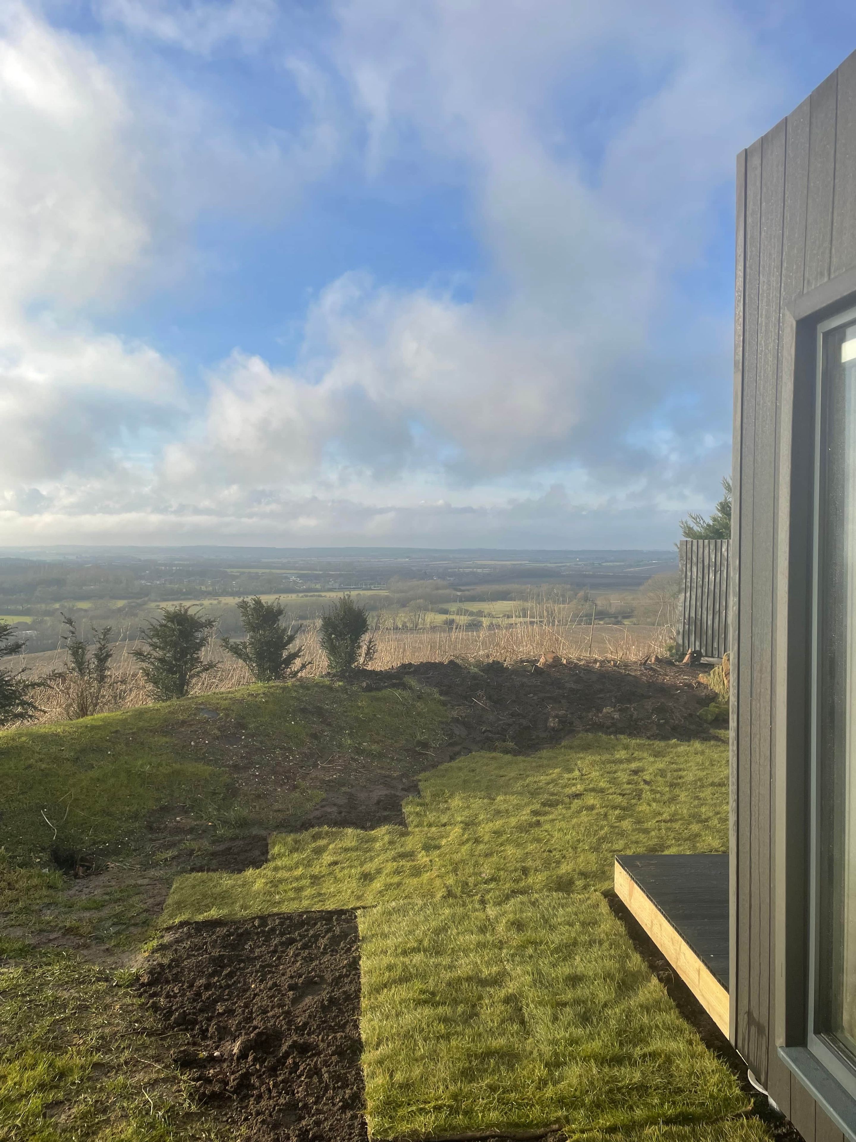 A view from a building's exterior, overlooking a grassy landscape with a clear sky.