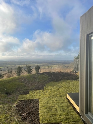 A view from a building's exterior, overlooking a grassy landscape with a clear sky.