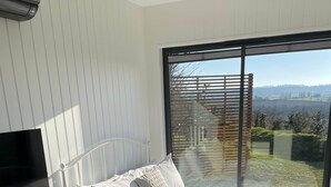 Een slaapkamer met een bed, een televisie, een bureau en uitzicht op het omliggende landschap.