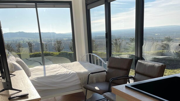 Een moderne slaapkamer met een groot bed, een bureau en twee stoelen.