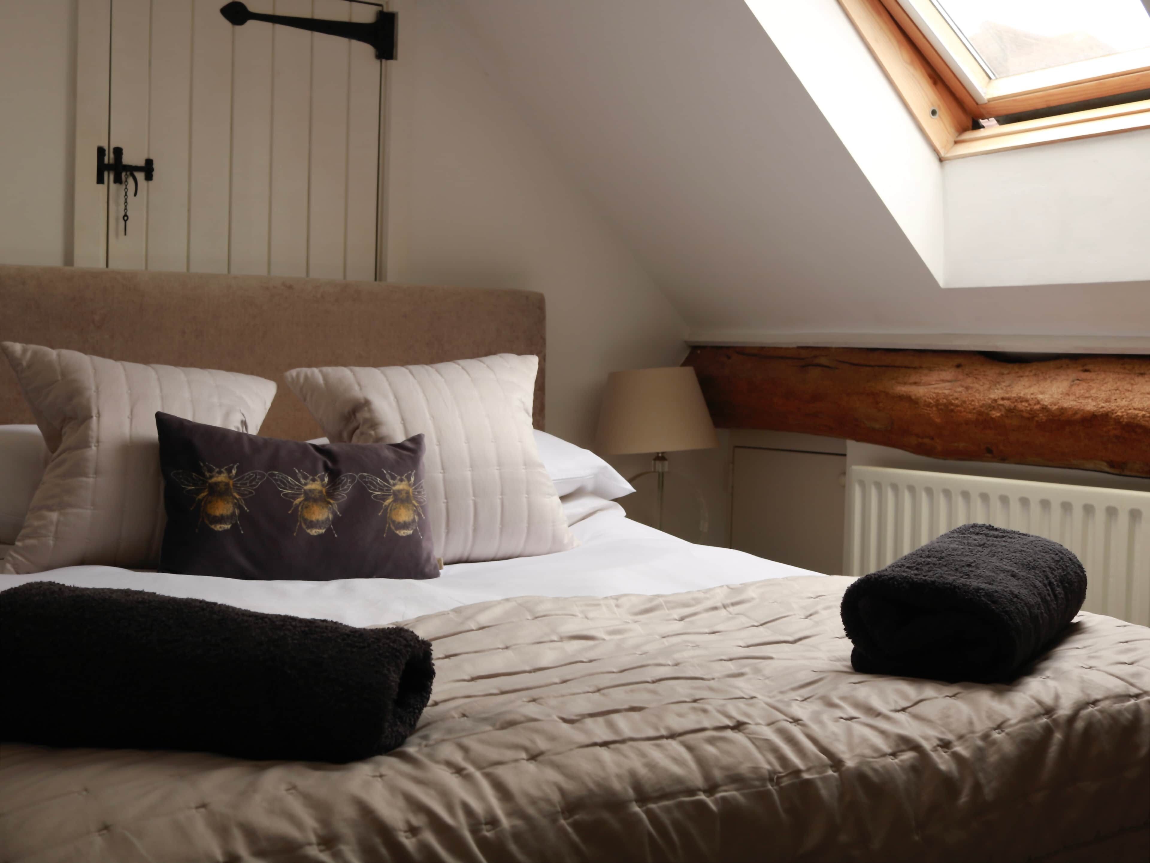 Un dormitorio con cama, almohadas, una ventana y un radiador.