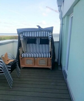 Eine Terrasse mit gestreiftem Baldachin und einer hölzernen Bank.