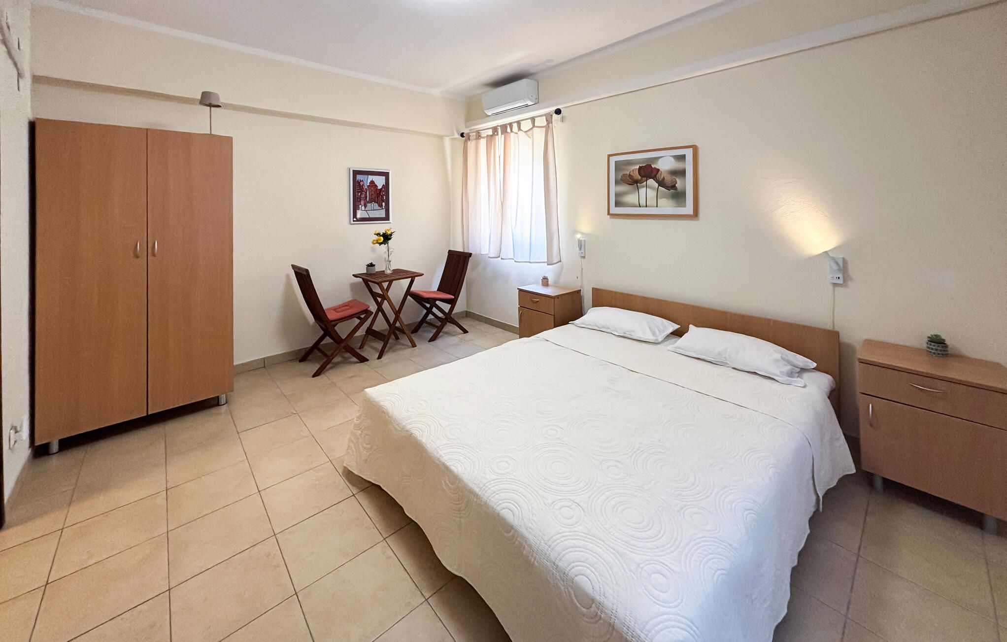 Una habitación de hotel con una cama, un escritorio, una silla, un armario y una ventana con cortinas.