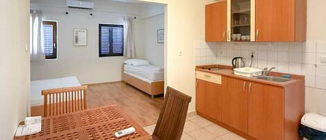Habitación compacta con kitchenette, una cama y comedor.