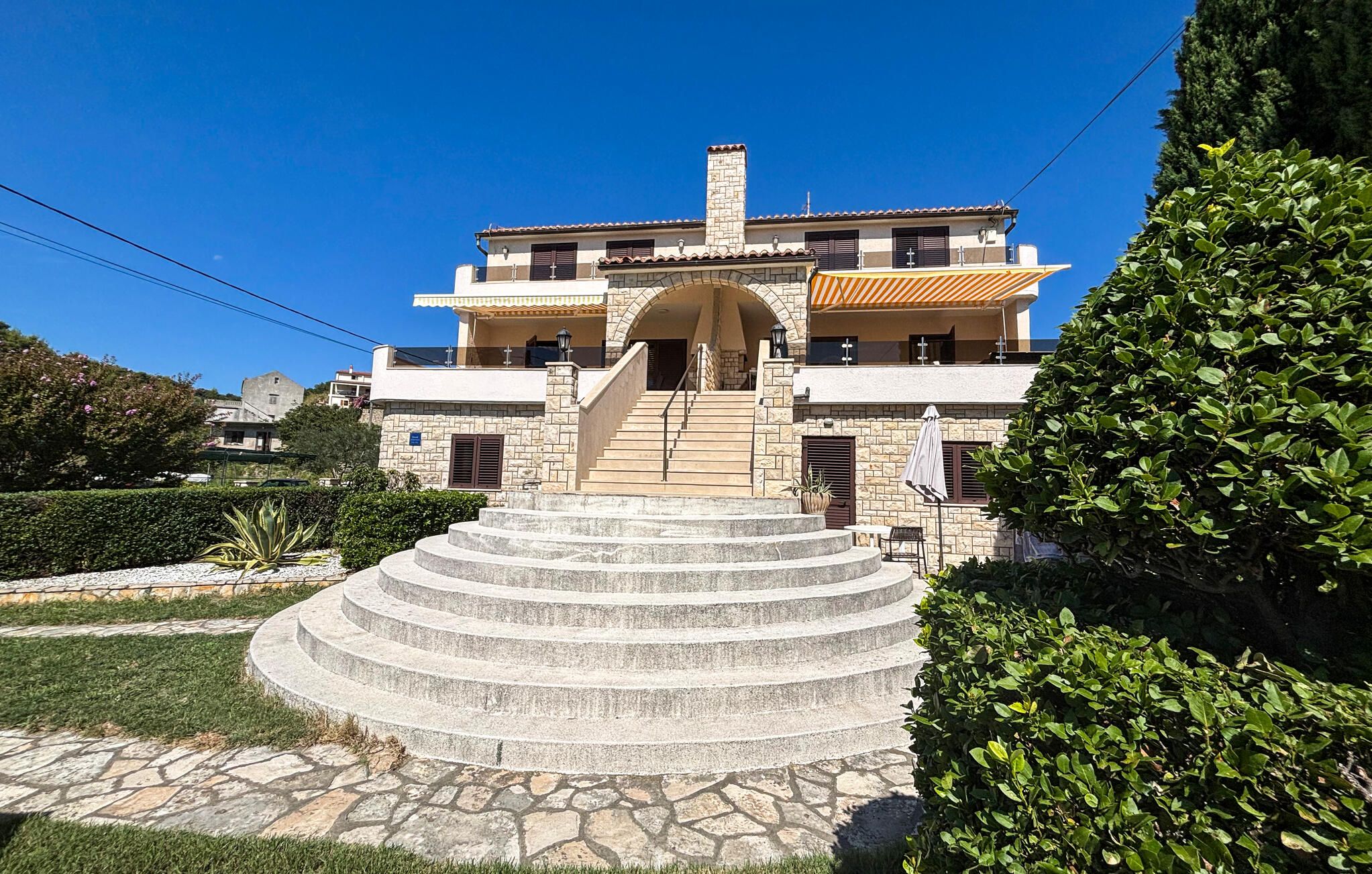 Un bâtiment à deux étages, avec un escalier en pierre menant à l’entrée.