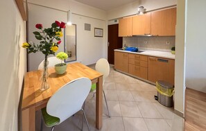 A compact kitchen with wooden cabinets, a sink, and a dining area with a table and chairs. - Awesome apartment in Rab with WiFi (Rab)