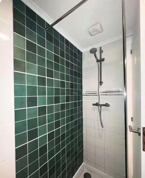 Ein Duschbereich mit Glastür und gefliesten Wänden.