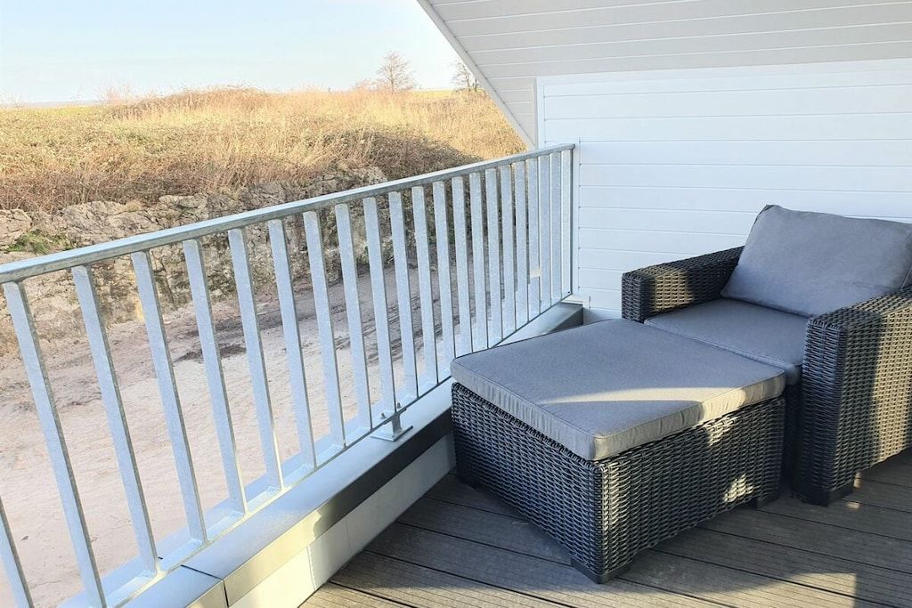 Ein Balkon mit Korbmöbeln und Blick auf den Strand.