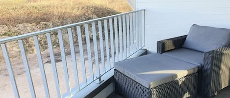 Ein Balkon mit Korbmöbeln und Blick auf den Strand.