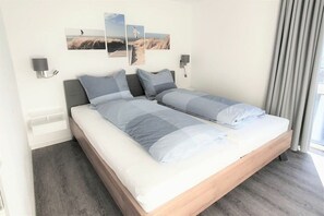 A double bed with a wooden frame, grey bedding, and a wall-mounted light fixture. - House No. 22, Deichgraf (Wangerland)