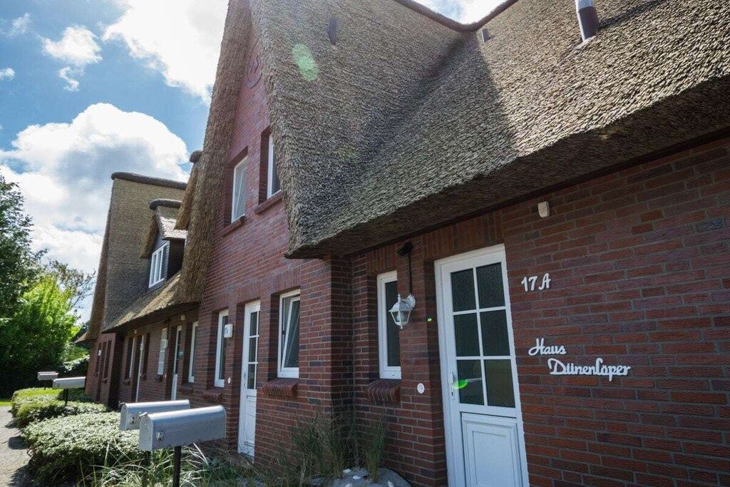A brick building with a traditional design, featuring a white door and windows, and a sign that reads 'Haus Dillenloper.'