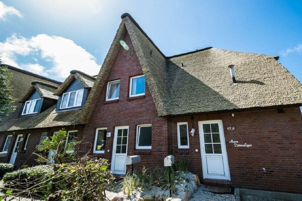 A row of red brick houses with white doors and windows, each with a small garden area in front. - Holiday home in St. Peter-Ording with Wi-Fi (St. Peter-Ording)