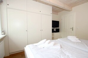 Ein Schlafzimmer mit einem Bett, einem weißen Wandschrank und einem Spiegel.