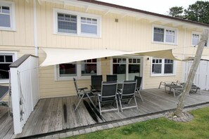 Ein Haus mit überdachter Terrasse und Gartenmöbeln.