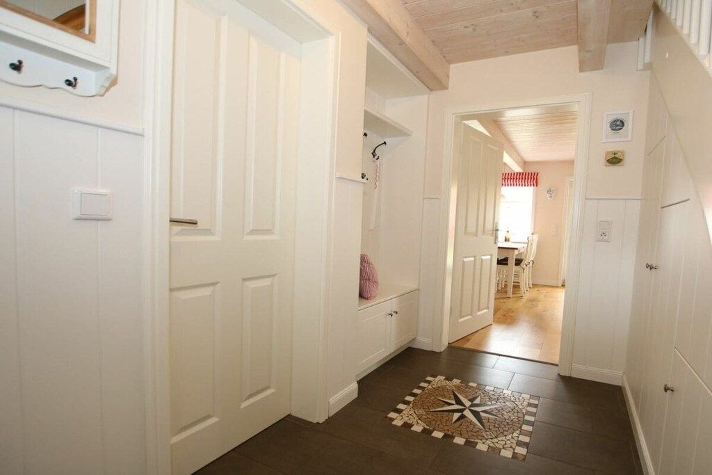 Un couloir avec des portes blanches, un tapis en forme d’étoile et un plafond en bois.