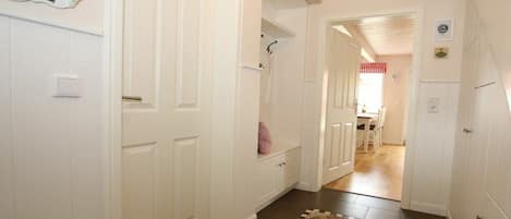 Un pasillo con puertas blancas, un tapete con forma de estrella y techo de madera.