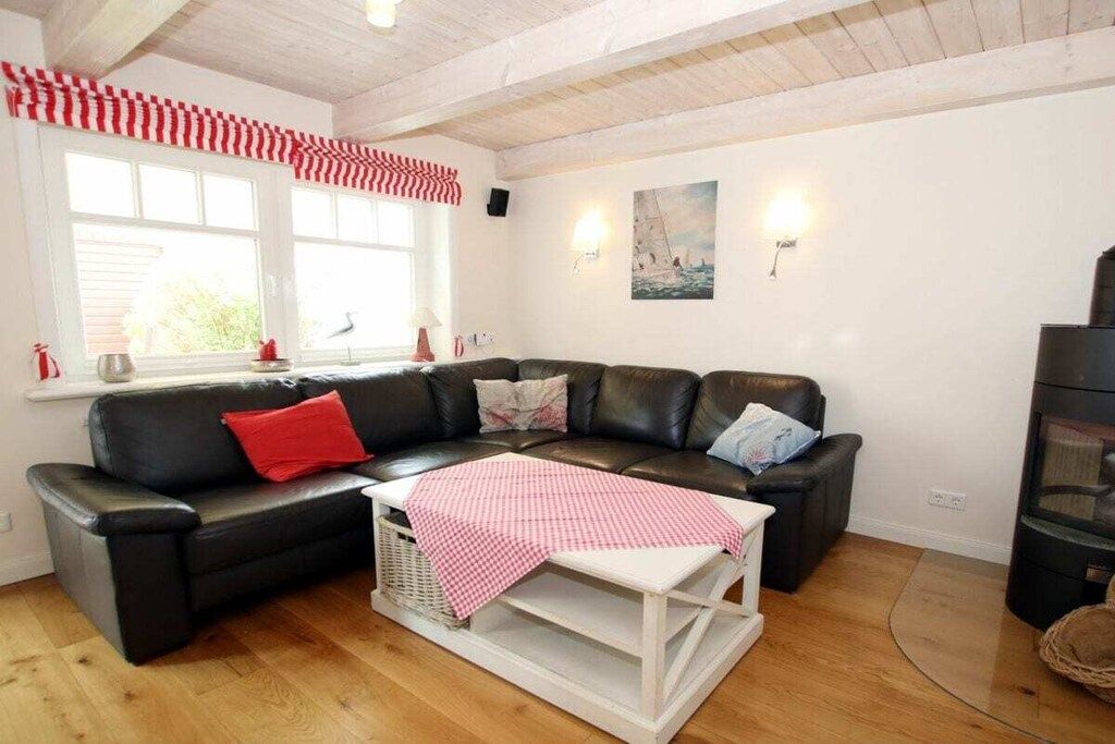 En stue med en sort lædersofa, et hvidt sofabord og en stribet gardin i rødt og hvidt.