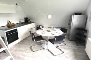 A compact kitchen with a dining area, including a stove, sink, and refrigerator. - Sonnengold Apartment Sonnengold (St. Peter-Ording)