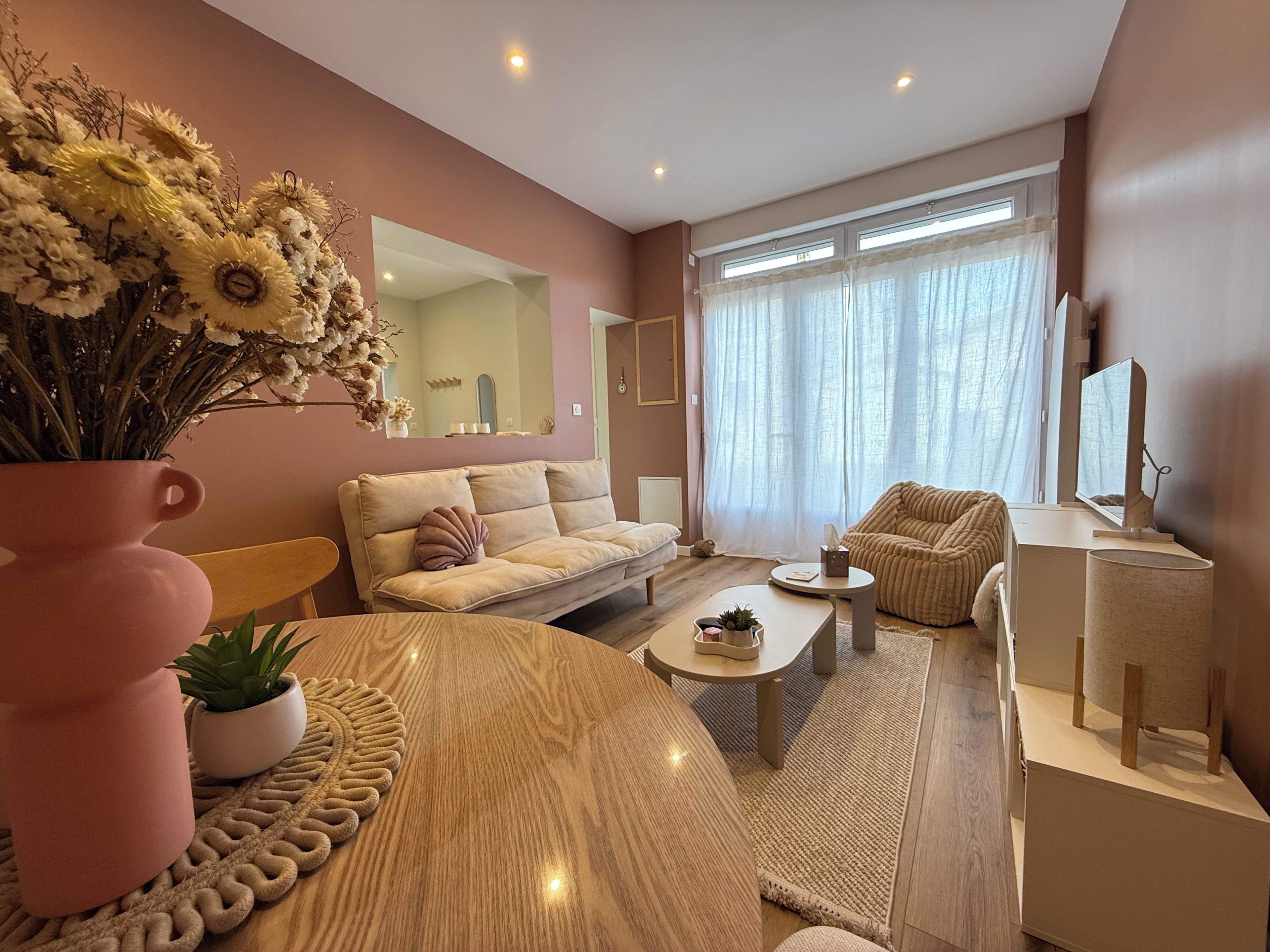 A modern living room with a sofa, armchair, coffee table, and a decorative vase with flowers.