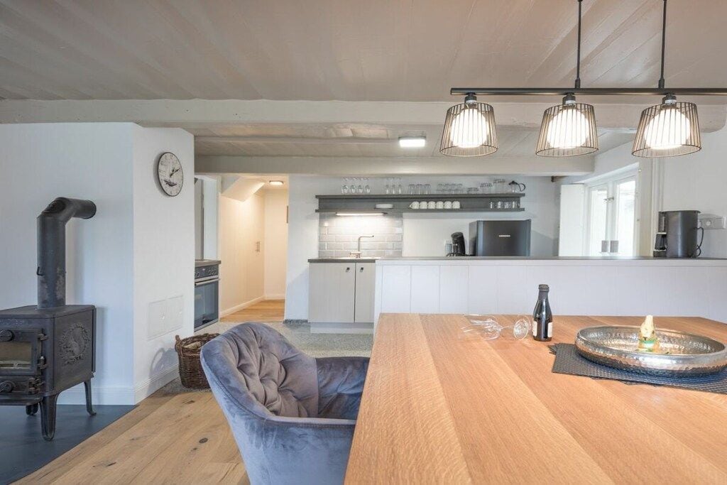 A modern kitchen with white cabinets, a built-in oven, and a coffee machine.
