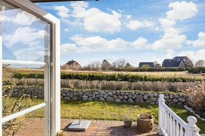 A patio with a stone wall, a potted plant, and a white railing. - Holiday apartment Watt'n Blick (Sylt-Ost)