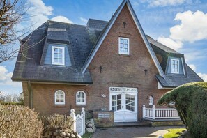 Ein zweistöckiges Backsteinhaus mit Giebeldach, einer Haustür und einer kleinen Veranda.
