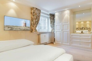 Ein Schlafzimmer mit einem Bett, einem Schminktisch, einem Spiegel und einem Fenster mit Vorhängen.