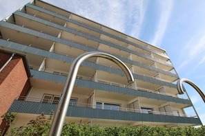 A multi-story building with balconies, a clear sky, and a metal structure in the foreground. - Holiday apartment in Föhr with 1 bedroom (Wyk auf Föhr)