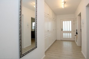 A hallway with white walls and wooden flooring, leading to a door with frosted glass panels. - Holiday apartment in Föhr with 1 bedroom (Wyk auf Föhr)