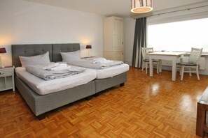 Ein Hotelzimmer mit einem Doppelbett, einem Schreibtisch mit Stühlen und einem Kleiderschrank.