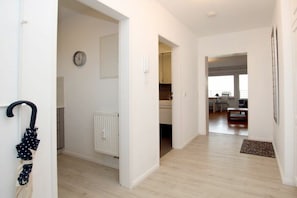A hallway with a radiator, a clock, and a door leading to a dining area. - Holiday apartment in Föhr with 1 bedroom (Wyk auf Föhr)