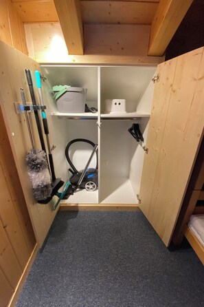 A compact storage space with shelves, a vacuum cleaner, and cleaning tools. - Schirli Dachgeschoss Appartement/Fewo, Bad, WC 6-Bettwohnung by Interhome (Rosswald)