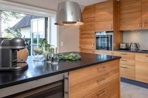 Eine moderne Küche mit Holzschränken, einer schwarzen Arbeitsplatte und einer Kaffeemaschine.