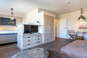 Un dormitorio moderno con cama, televisión, armario y zona de comedor con mesa y sillas.