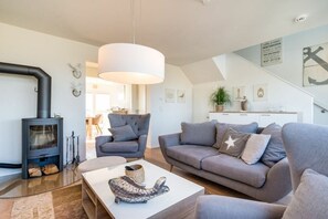 A modern living room with a fireplace, grey sofas, a white coffee table, and a staircase leading to an upper level. - Cape Mar at the quayside (Kappeln)
