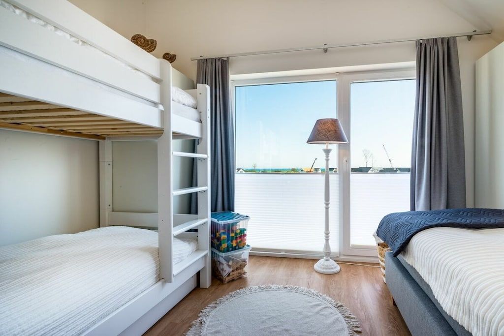 A room with bunk beds, a lamp, a view of the water, and a storage unit.