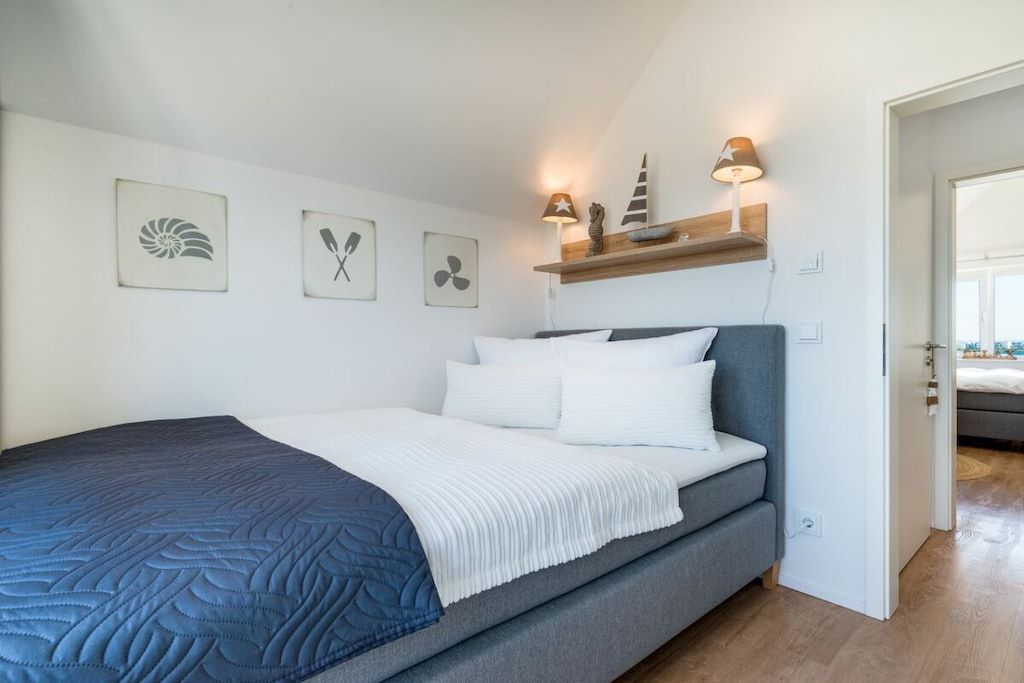 Une chambre à coucher comprenant un lit, une table de chevet, des œuvres d’art murales et une étagère avec des objets décoratifs.