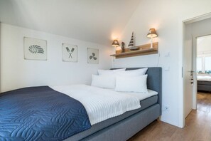 Une chambre à coucher comprenant un lit, une table de chevet, des œuvres d’art murales et une étagère avec des objets décoratifs.
