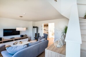 Un salon moderne doté d’un téléviseur à écran plat, d’une cheminée et d’un escalier menant à un niveau supérieur.