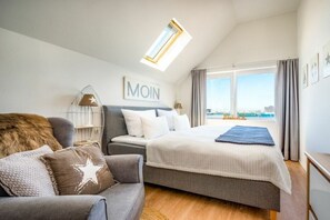 Ein Schlafzimmer mit Bett, Sofa, Oberlicht, Fenster und einem an der Wand befestigten Kunstwerk.