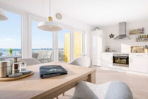 A modern kitchen with white cabinets, a built-in oven, and a view of the sea. - Cape Mar at the quayside (Kappeln)