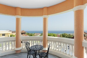 Ein überdachter Balkon mit Tisch und Stühlen mit Blick auf die Küste.