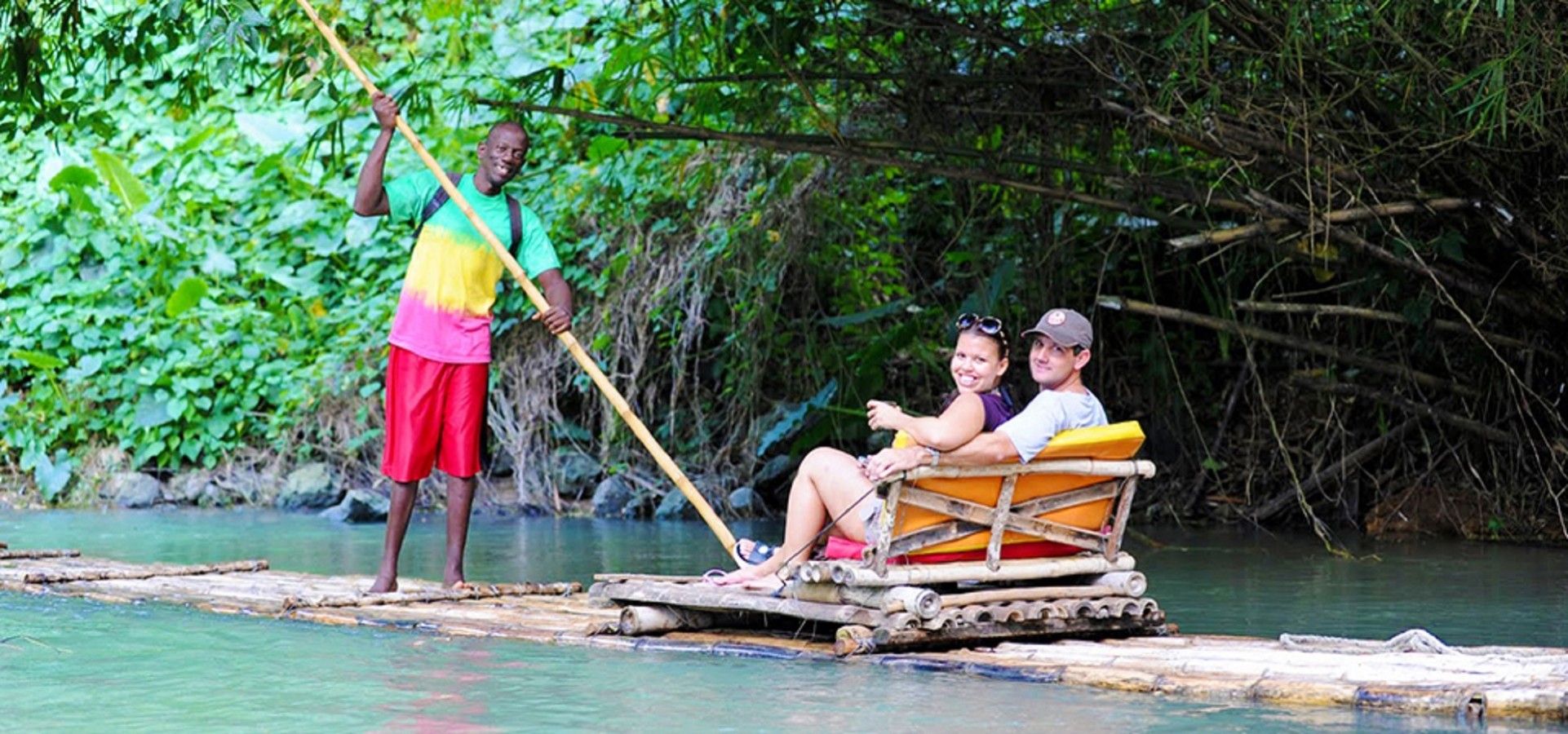 A river scene with a wooden raft carrying two people and a guide.