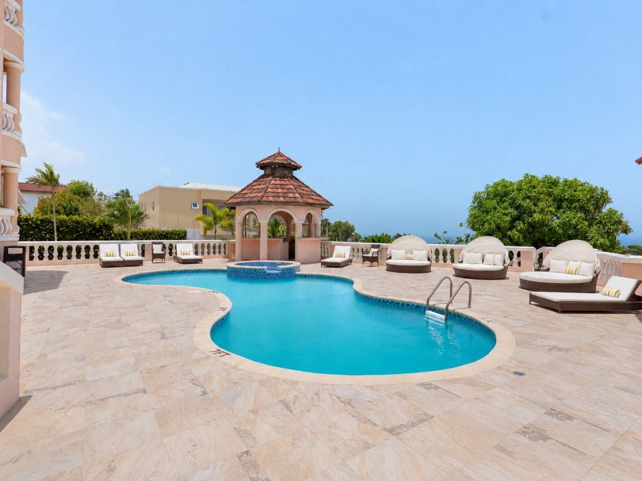 Un espace piscine comprenant un jacuzzi, des chaises longues et un gazebo.