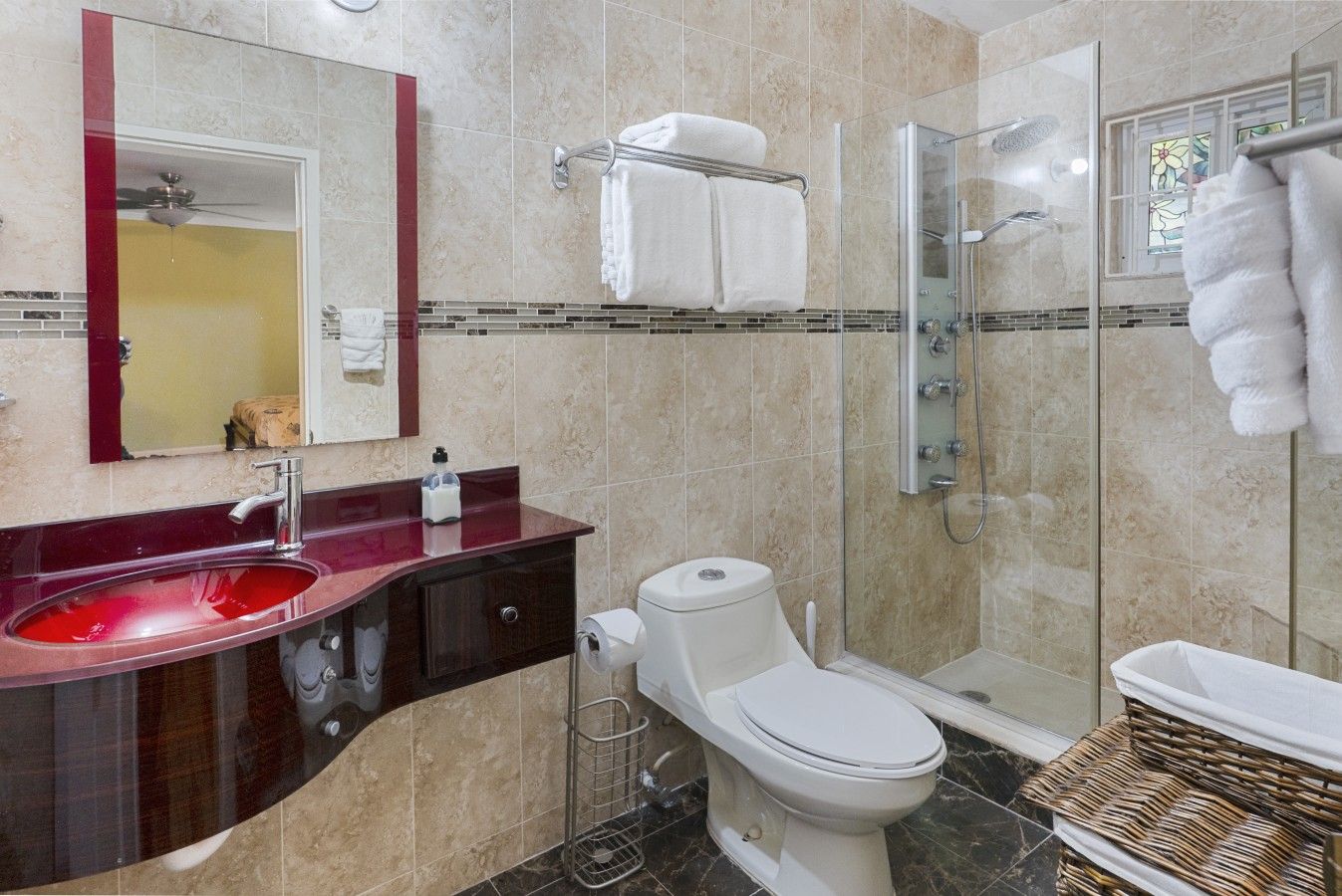 A modern bathroom with a glass-enclosed shower, a red sink, and a toilet.