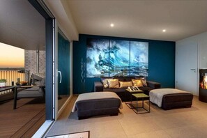 A modern living room with a sofa, ottoman, and a large painting on the wall. - Wellness Apartment The Wave (Olpenitz)