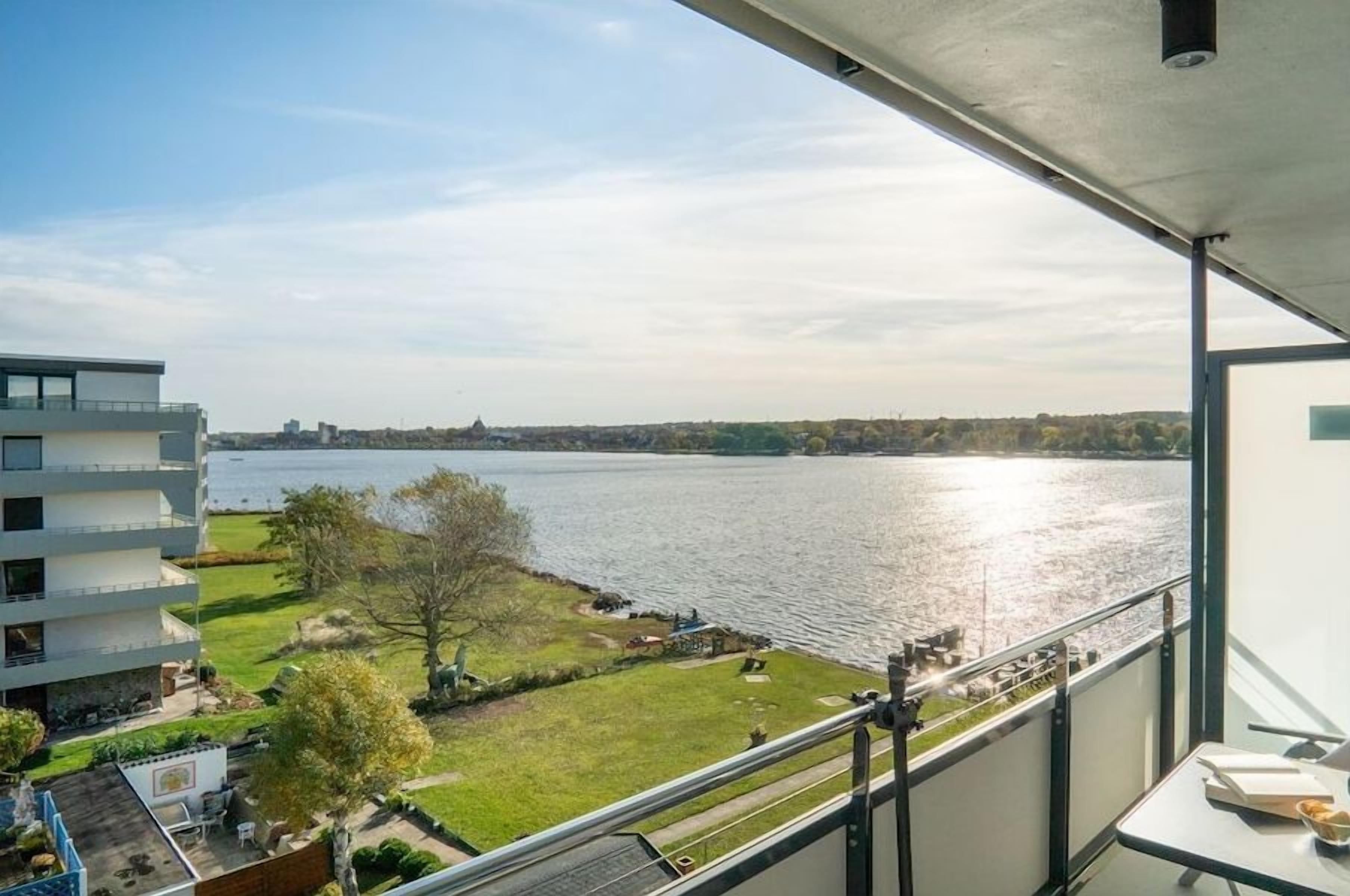 Un balcon avec vue sur une rivière et sur le paysage urbain.